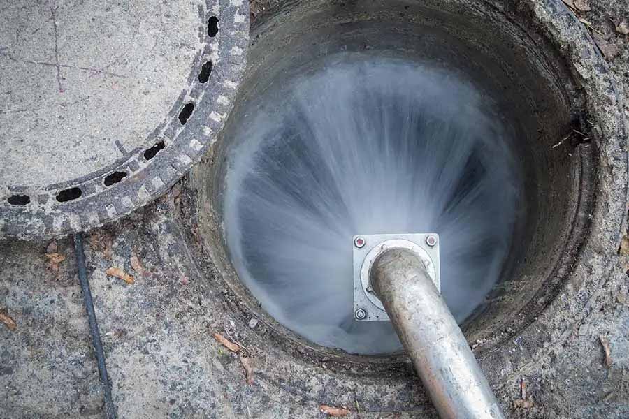High-pressure water jet cleaning a sewer line