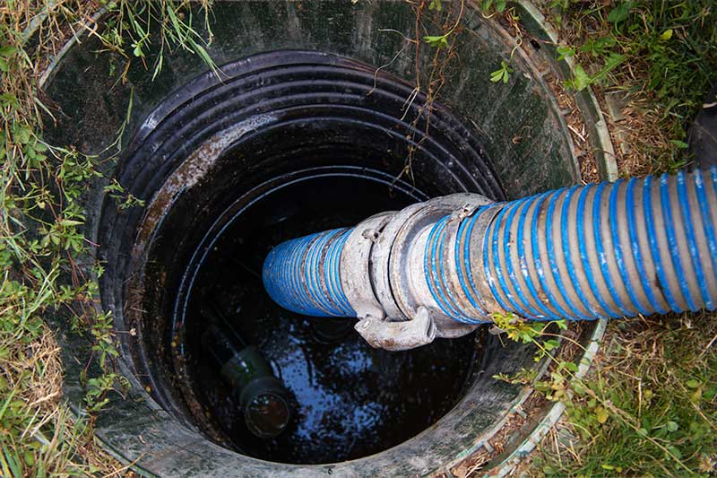 Blue hose draining water from septic tank